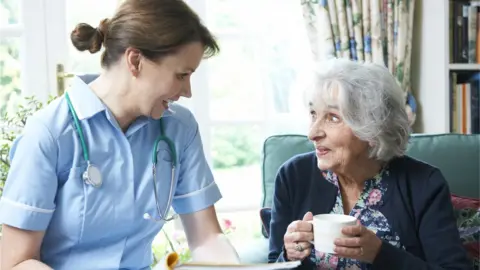 Getty Images Nurse speaking to woman in care home