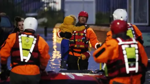 Getty Images South Yorkshire Fire and Rescue Service carry a child through floods in Doncaster on Friday 8 November