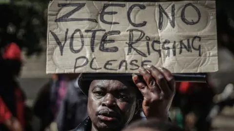 AFP A protester waves a placard demanding transparency in Bulawayo, Zimbabwe 13 July 2018