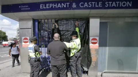 PA Media Police officers close the gates at Elephant & Castle station
