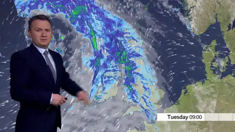 Weather forecaster Matt Taylor in front of UK map showing rains