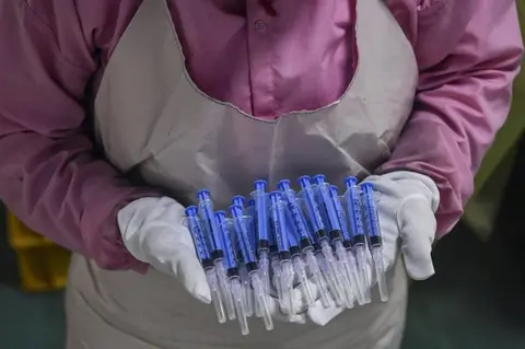 AFP In this photograph taken on September 2, 2020, a worker displays syringes at the Hindustan Syringes factory in Faridabad. - India's biggest syringe manufacturer is ramping up its production to churn out a billion units