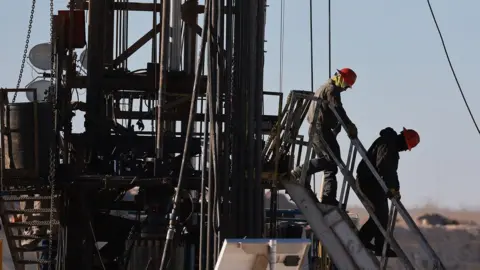 Getty Images Workers place pipe into the ground on an oil drilling rig set up in the Permian Basin oil field on March 12, 2022 in Midland, Texas. President Joe Biden imposed a ban on Russian oil, the world’s third-largest oil producer, which may mean that oil producers in the Permian Basin will need to pump more oil to meet demand. The Permian Basin is the largest petroleum-producing basin in the United States.