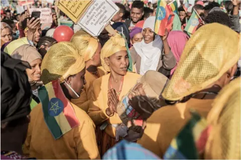 AFP A group of women at a protest wearing yellow and holding Ethiopian flags.