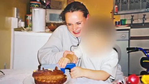 Rosie Hall Claire Holland and one of her children cutting a birthday cake