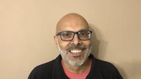 JOHN DEVINE/BBC Piyush Gupta smiling at the camera