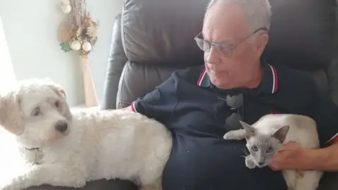 Carol Monk Bobby the dog, Allan Baker and Ashley the cat all sat on a chair