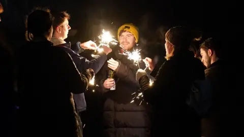 PA Media Revellers on Carlton Hill light sparklers during the Hogmanay New Year celebrations in Edinburgh. Picture date: Sunday January1, 2023