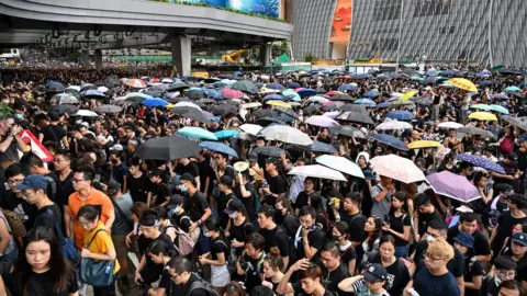 Getty Images Protesters carry umbrellas during a march to the West Kowloon rail terminus against the proposed extradition bill and before a clash with police in the Mong Kok district in Kowloon in Hong Kong on July 7, 2019