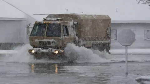 Getty Images A National Guard vehicle patrols streets in flooded Massachusetts