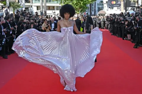 AFP A woman poses in an iridescent dress on the red carpet.