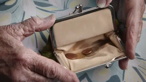 Getty Images Someone's hands holding a nearly empty purse