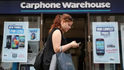 Getty Images Woman walks past Carphone Warehouse store