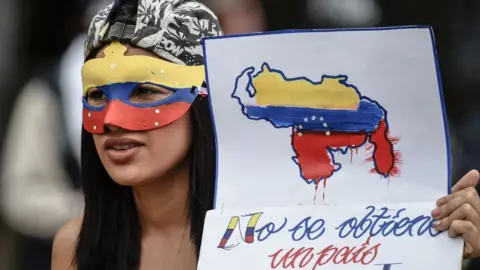 AFP A young opposition activist holds a sign reading "we can't get a different country", during a protest against the government in Caracas, on June 29, 2017