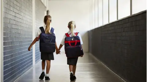 Getty Images Two young girls walking hand in hand at school