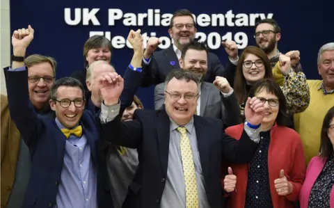 PA Media Stephen Farry celebrates with his Alliance Party colleagues