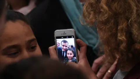 AFP A Tunisian child takes a selfie with French President Emmanuel Macron during a ceremony in memory of the victims of a deadly Islamic State group attack in 2015 at Tunis" Bardo Museum on February 1, 2018.