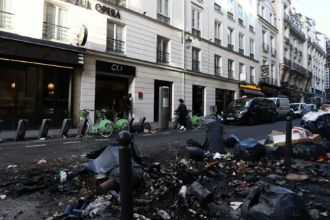 YVES HERMAN/Rueters A view shows burnt rubbish and damage in a street the day after clashes during protests over French government's pension reform in Paris, France, March 24, 2023.