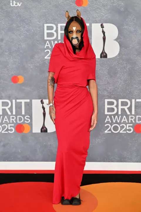 Getty Images A woman with a facemask depicting a horse at the 2025 Brit Awards