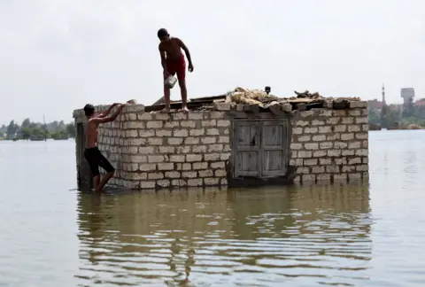 MOHAMED ABD EL GHANY / REUTERS Two boys climb a brick home. Its roof appears to be missing.