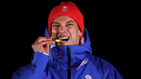 Matt Weston bites gold medal on podium after winning skeleton at winter olympics in cortina, italy