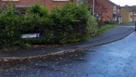 Wardleworth Way - a road on a housing estate with cars and vans parked and a number of brick houses