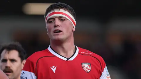 Freddie Thomas standing on the pitch wearing Gloucester kit and head tape during a match in October 2025 