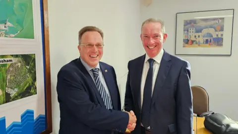 Former Labour councillor Charles Woodgate shakes hands with leader of the Conservatives in Dover after he defected from Labour 