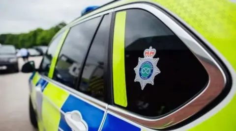 Staffordshire Police The side of a police car with yellow and blue squares on it