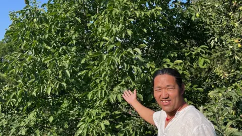 Julie Kleeman Yeshi Jampa smiling whilst pointing towards the tree.