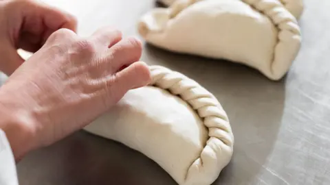 A pair of hands crimping a pasty.