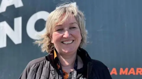 Laura Sawyer, who has shoulder length blonde hair and is wearing a black jacket and polo shirt.