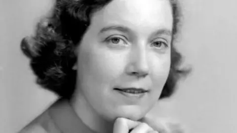 Leeds City Council A black and white headshot of a woman with short curly dark hair. She is smiling at the camera.