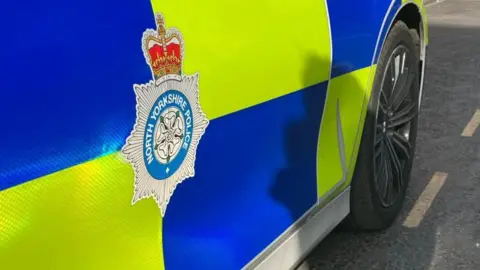 BBC North Yorkshire Police logo on the side of a police car.