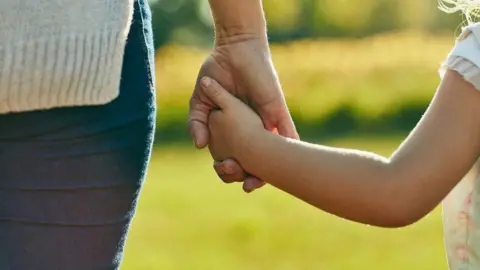 Getty Images Adult holds child's hand