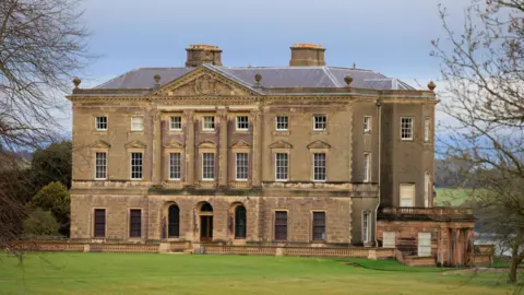 Liam McBurney/PA Wire Castle Ward in County Down - an ornate 18th-century mansion overlooking Strangford Lough. The entrance side of the building is in a classical Palladian style with columns supporting a triangular pediment. A lawn stretches out in front of the building. 