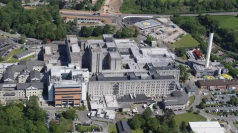BBC An aerial view of Derriford Hospital, with a helipad seen in the right hand corner surrounded by bits of trees and greenery