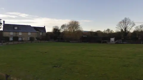 A shot of an empty field with a house at the rear end
