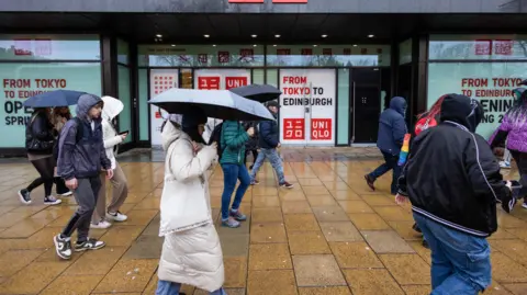 People walking past shops in the rain