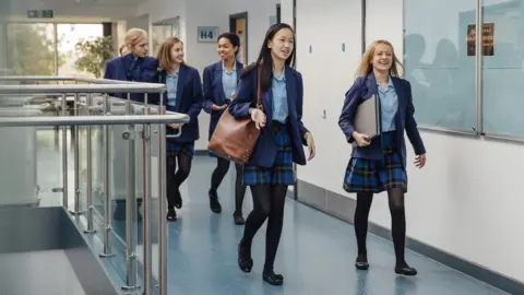 DGLimages Group of students are walking down the school corridor together wearing uniform.