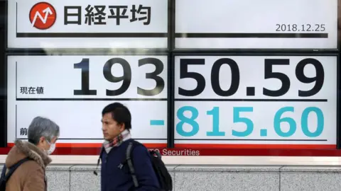 EPA Pedestrians walk past a stock market indicator board in Tokyo, Japan, 25 December 2018