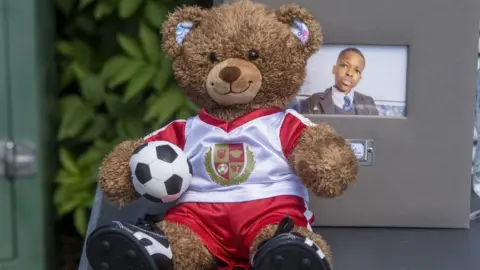 PA Media a teddy bear in an Arsenal kit was laid at the vigil for Daniel