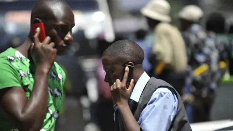 AFP People walk while speaking on the phone on 1 October 2012 in Nairobi, Kenya.