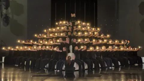 LMA University The dance group dressed all in black holding candles in outstretched arms as part of a choreographed routine.