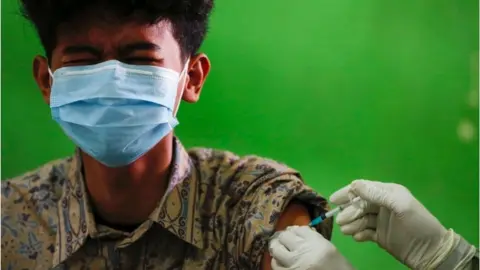 Reuters An Indonesian student reacts as he receives his first dose of China's Sinovac Biotech vaccine for the coronavirus disease (COVID-19) at a high school, as the cases surge in Jakarta, Indonesia, 1 July 2021.