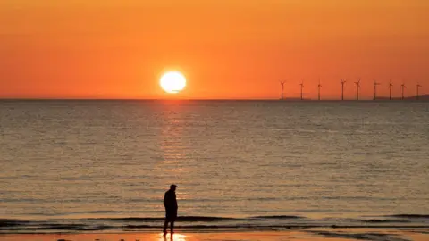 Lorraine Lamb Sunset over the sea with man silhouetted on the beach