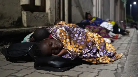 AFP Congolese fleeing from Goma, Democratic Republic of Congo (DRC), sleep with their belongings on a street after the Nyiragongo volcano erupted near the border in Gisenyi, Rwanda, on 23 May 2021