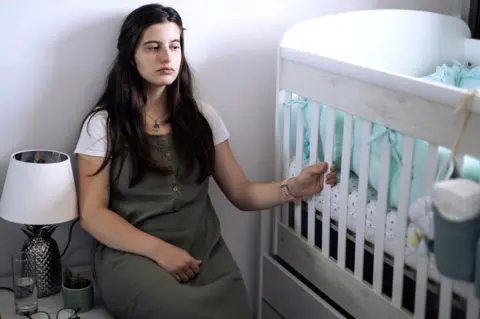 Getty Images mum sitting beside empty cot