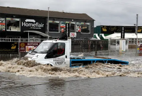 Getty Images A man drives a truck through flood waters