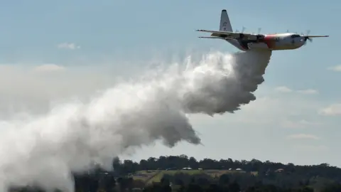 Getty Images A NSW Rural Fire Services Hercules C-130 large air tanker drops water in an exercise over western Sydney in 2017